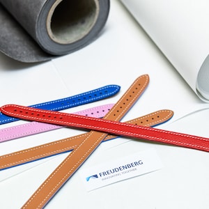 May include: Five leather watch bands in different colors: blue, pink, brown, tan, and red. The bands are arranged in a criss-cross pattern on a white surface. The text "FREUDENBERG INNOVATING TOGETHER" is visible in the lower right corner of the image.