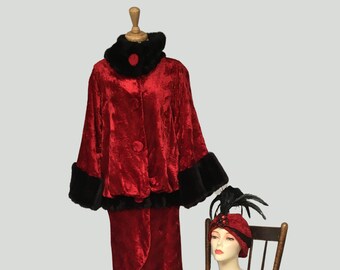 May include: A red velvet dress with a black fur collar and cuffs, displayed on a wooden mannequin. A red hat with black feathers sits on a wooden chair.