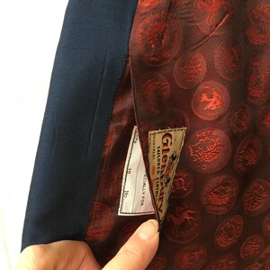 May include: A navy blue blazer with a red lining featuring a repeating pattern of small gold circles with different designs. The lining has a label that reads "Glenbarry Tailored Clothing" and "Specially for Montreal."