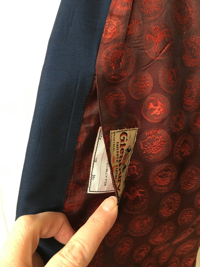 May include: A navy blue blazer with a red lining featuring a repeating pattern of small gold circles with different designs. The lining has a label that reads "Glenbarry Tailored Clothing" and "Specially for Montreal."