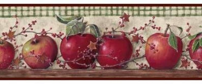 May include: Red apples with green leaves and red berries on a white and green checkered background. The apples are arranged in a row with the stems facing up. The background is a light brown color.