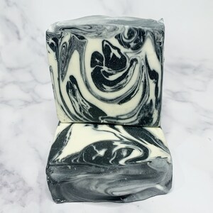 May include: Two bars of handmade soap with a black and white marbled swirl pattern. The soap is stacked on top of each other.