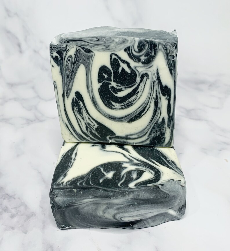 May include: Two bars of handmade soap with a black and white marbled swirl pattern. The soap is stacked on top of each other.