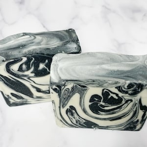 May include: Two bars of handmade soap with a black and white marbled design. The soap is made with natural ingredients and is perfect for all skin types.