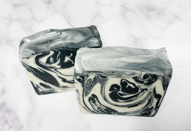 May include: Two bars of handmade soap with a black and white marbled design. The soap is made with natural ingredients and is perfect for all skin types.