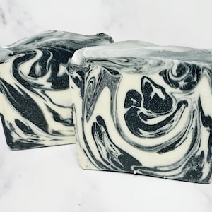 May include: Two bars of handmade soap with a black and white marbled design. The soap is made with natural ingredients and is perfect for all skin types.