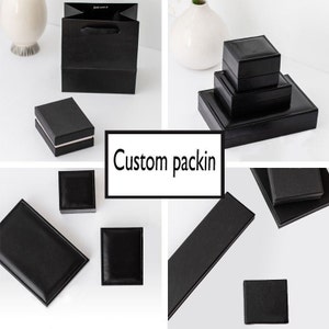 May include: A set of black gift boxes of various sizes, including a small square box, a rectangular box, and a larger box with a lid. The boxes are made of a smooth, black material and have a simple, elegant design.  The boxes are perfect for packaging small gifts or jewelry.