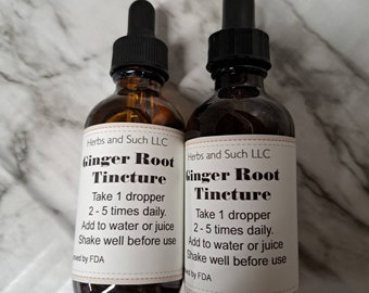 May include: Two brown glass bottles with dropper tops, labeled "Ginger Root Tincture". The bottles contain a clear liquid and have white labels with black text. The text on the labels includes instructions for use, such as "Take 1 dropper 2-5 times daily" and "Add to water or juice".