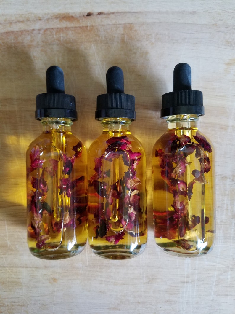 Puede incluir: Tres botellas de vidrio con goteros negros llenos de un l&iacute;quido amarillo y p&eacute;talos de rosa secos.