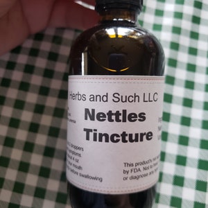 May include: A brown glass bottle with a dropper top and a white label that reads "Herbs and Such LLC Nettles Tincture". The label also includes instructions for use and a disclaimer stating that the product is not to be used to treat or diagnose any illness.