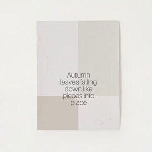 May include: A beige and white card with the text "Autumn leaves falling down like pieces into place" printed in black. The card has a simple design with a few small leaf drawings.