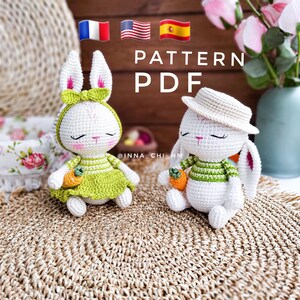 May include: Two crocheted bunny amigurumi toys, one wearing a green dress and the other a straw hat, both holding carrots. The toys are sitting on a woven mat with the text "PATTERN PDF" above them.