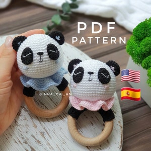 May include: Two crocheted panda rattle toys with wooden rings. The panda on the left is white with blue ruffle trim and the panda on the right is white with pink ruffle trim. The text "PDF PATTERN" is above the toys.