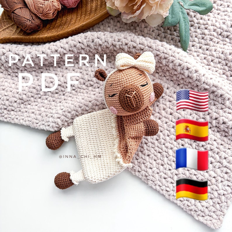 May include: Crochet pattern PDF for a brown and white llama amigurumi toy. The pattern is available in English, Spanish, French, and German. The llama is wearing a white blanket and has a pink bow on its head.