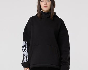 May include: Black hoodie and matching pants set. The hoodie features a kangaroo pocket and text on the left sleeve. The pants have a dragon design on the lower right leg. The outfit is made of a soft material.