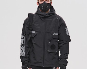 May include: Black tactical jacket with multiple pockets, a hood, and a face mask. The outfit includes matching black cargo pants with straps and black sneakers. White Japanese characters are printed on the jacket and pants.