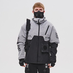 Könnte beinhalten: Ein futuristisch anmutendes Outfit in Grau und Schwarz. Das Ensemble umfasst eine Kapuzenjacke, Cargohose und eine Gesichtsmaske. Die Jacke hat ein zweifarbiges Design mit Taschen und grafischen Details. Die Hose hat Riemen und mehrere Taschen. Das Outfit wird durch schwarze Handschuhe und Stiefel vervollständigt.