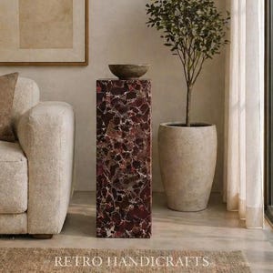 May include: A tall, rectangular pedestal with a dark red and white speckled pattern, topped with a small, round, gray bowl. A potted tree and a beige sofa are in the background. The text "RETRO HANDICRAFTS" is at the bottom.