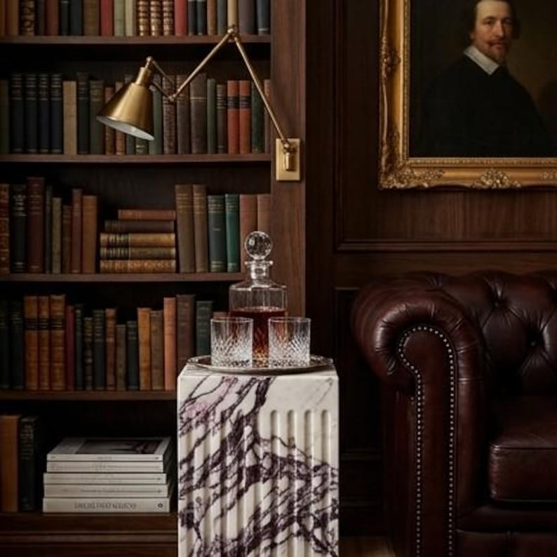 May include: A square white marble pedestal with deep purple veining, featuring a fluted design. On top sits a clear glass decanter filled with amber liquid and two matching crystal tumblers with a diamond-cut pattern on a silver tray.