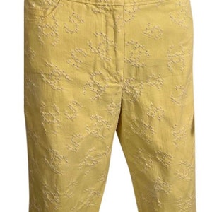 Puede incluir: Pantalones cortos de algodón amarillo con un estampado floral bordado. Los pantalones cortos tienen cierre de botón y cremallera y dos bolsillos delanteros.
