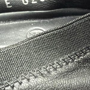 May include: A black leather shoe interior featuring a textured elastic trim with visible zigzag stitching. The inner lining displays the stamped alphanumeric code E 626642 in white ink, along with a faint circular logo embossed on the footbed surface.
