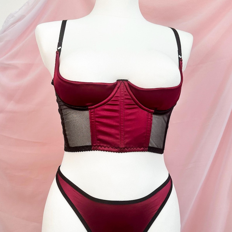 Op de afbeelding: Een bordeaux satijnen en zwart mesh lingerie top met een sweetheart halslijn en verstelbare bandjes.