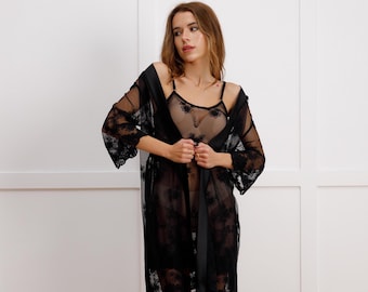 May include: A black lace robe with a satin sash. The robe has a sheer, delicate fabric and features a floral pattern.