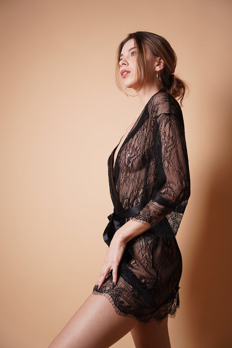 K&ouml;nnte beinhalten: Eine schwarze Spitzenrobe mit einem Satinband. Die Robe ist durchsichtig und hat ein zartes Blumenmuster.