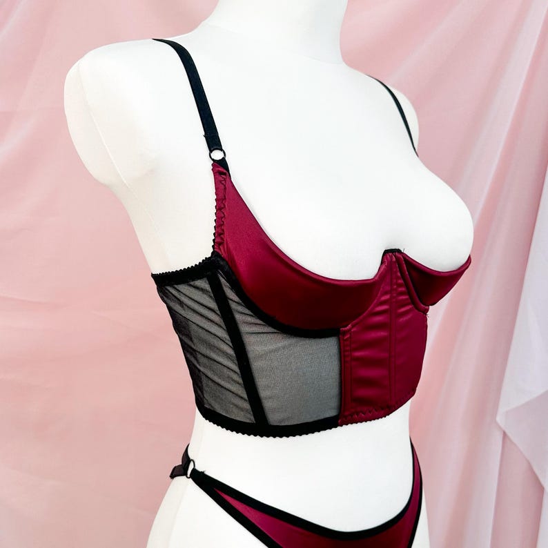 Op de afbeelding: Een lingerie top van bordeaux satijn en zwart mesh met verstelbare bandjes. De top heeft een sweetheart halslijn en een corset-stijl lijfje.
