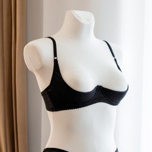 Könnte beinhalten: Ein schwarzer Lingerie-BH mit verstellbaren Trägern und einem tiefen Ausschnitt.