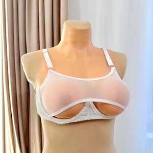 May include: A white open-cup bra featuring sheer mesh fabric across the upper portion of the cups, solid white trim along the edges, and adjustable shoulder straps. The design includes a supportive underwire structure and a classic hook-and-eye closure.