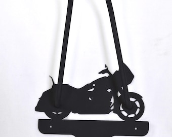 Könnte beinhalten: Schwarze Metall-Motorrad-Silhouette Wanddekoration. Das Motorraddesign umfasst einen gebogenen Lenker, Räder und einen Sitz. Die Wanddekoration hat unten einen Haken zum Aufhängen von Gegenständen. Das Motorrad ist etwa 46 cm hoch.