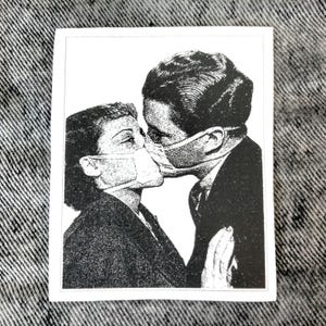 May include: Black and white sticker featuring a vintage illustration of a couple kissing while wearing face masks. The image is a retro-style design with a white border, perfect for adding a unique touch to any surface.