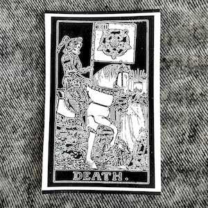 May include: A rectangular black and white patch featuring a detailed illustration of a skeleton in armor riding a horse, holding a flag with a rose emblem and the Roman numeral XIII. The word DEATH is printed in white capital letters at the bottom.