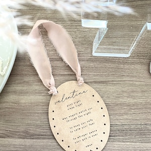 May include: A light brown oval wooden sign with the text "valentina" and a prayer for a good night's sleep. The sign is decorated with small dots and a cross at the bottom.