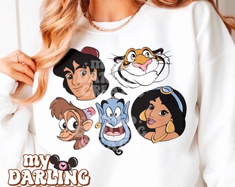 May include: White sweatshirt with a graphic print of characters from the Disney movie Aladdin. The characters include Aladdin, Jasmine, Abu, Genie, and Rajah. The text "my darling creates" is printed on the bottom of the sweatshirt.