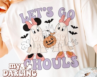 May include: White t-shirt with a graphic of two cartoon ghosts holding a jack-o-lantern. The text "Let's Go Ghoul's" is printed in purple on the shirt. The text "my darling creates" is printed in pink at the bottom of the shirt.