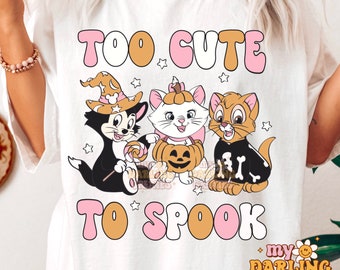 May include: White t-shirt with a pink and gold graphic that says "Too Cute To Spook" and features three cartoon cats dressed in Halloween costumes. The text "my darling creates" is in the bottom right corner.