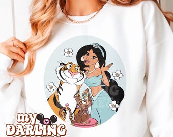 May include: A white sweatshirt with a circular graphic featuring Jasmine from Aladdin, Rajah the tiger, and Abu the monkey. The graphic is surrounded by white flowers and has a light blue background. The text "my darling creates" is printed in the bottom left corner.