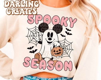May include: A cream colored sweatshirt with a pink "Spooky Season" graphic featuring a cartoon ghost Mickey Mouse holding a jack-o-lantern. The text "My Darling Creates" is in the top left corner.