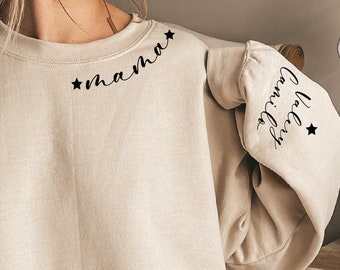 Puede incluir: Una sudadera beige con el texto "mama" en el hombro izquierdo y "hello sunshine" en la manga derecha.
