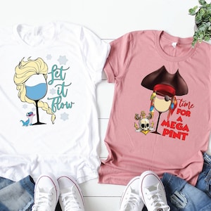 Può includere: Due t-shirt con un design a forma di bicchiere di vino. La t-shirt bianca presenta un bicchiere di vino con un'immagine di cartone animato di Elsa di Frozen con il testo "Let it flow". La t-shirt rosa presenta un bicchiere di vino con un'immagine di cartone animato di Captain Jack Sparrow con il testo "Time for a mega pint".