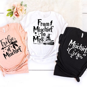 May include: Three t-shirts with a Harry Potter theme. The first shirt is peach and says "Tribe of Mischief". The second shirt is white and says "From Mischief to Mrs." with a witch's hat and broom. The third shirt is black and says "Mischief Crew" with a lightning bolt and stars.