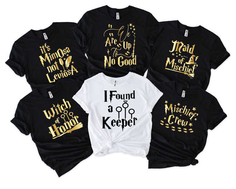 May include: A collection of black and white t-shirts with gold text. The shirts feature phrases like "It's Mimosa not Leviosa", "We Are Up To No Good", "Maid of Mischief", "Witch of Honor", "I Found a Keeper", and "Mischief Crew".