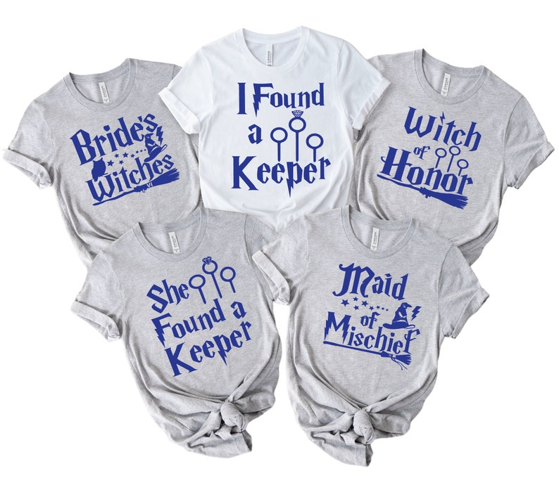 May include: Five t-shirts with blue text on a white or gray background. The shirts have phrases like "Brides Witches", "I Found a Keeper", "Witch of Honor", "She Found a Keeper", and "Maid of Mischief". The shirts are likely for a bridal party.