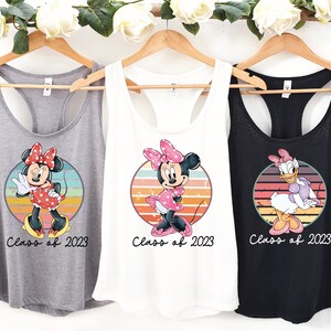 May include: Three tank tops with different Disney characters. The first tank top is gray with a vintage-style image of Minnie Mouse and the text "Class of 2023". The second tank top is white with a vintage-style image of Minnie Mouse and the text "Class of 2023". The third tank top is black with a vintage-style image of Daisy Duck and the text "Class of 2023".