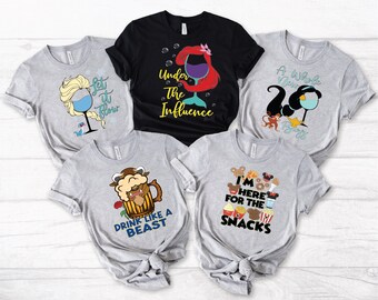 Puede incluir: Cinco camisetas grises con diferentes diseños de temática Disney. Las camisetas presentan personajes como Ariel, Elsa, la Bestia y Mickey Mouse. Las camisetas tienen texto que dice "Under the Influence", "Let it Flow", "Drink Like a Beast", "A Whole New Brew", y "I'm Here for the Snacks".