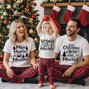 May include: Three white t-shirts with black text and holiday graphics. The adult shirts read Mom Manager of Mischief and Christmas is Better with Mischief. The child shirt reads Wrapped in Mischief with a stocking, candy cane, and gift box.