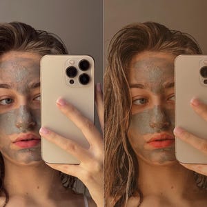 May include: A person with a gray face mask is taking a selfie with a gold iPhone. The phone is held in front of their face, covering part of their face and hair.