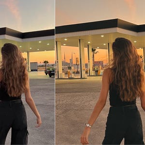 May include: A person with long brown hair wearing a black tank top and black pants stands in front of a gas station with a sunset in the background.